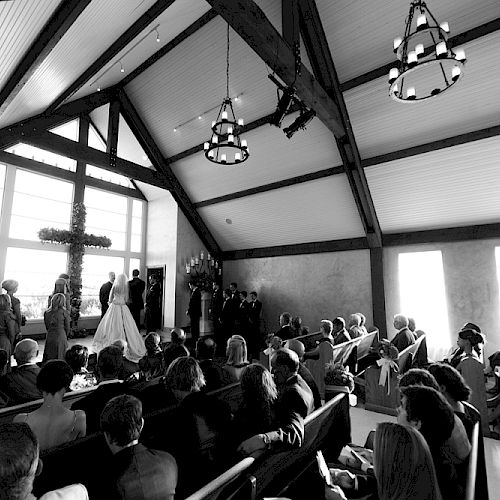 This image depicts a black-and-white scene of a wedding ceremony taking place inside a church filled with seated guests.