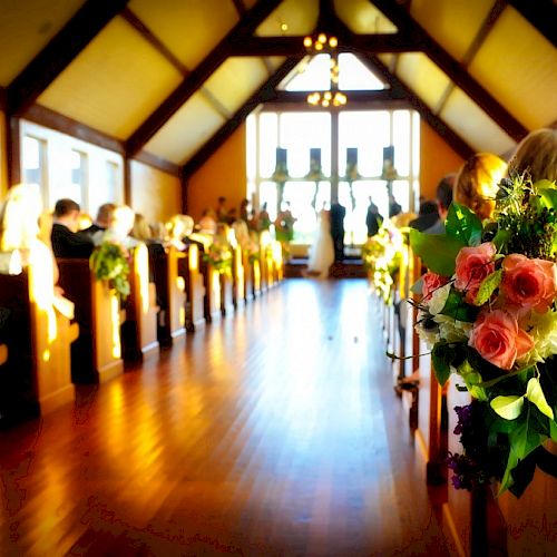 The image depicts an indoor wedding ceremony in a wooden chapel, with flower arrangements on pews and guests seated, facing the altar.