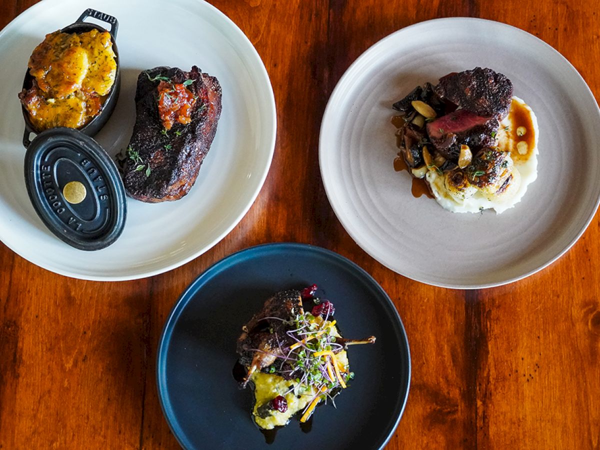 The image shows three plates of gourmet food, featuring steak, mashed potatoes, vegetables, and a baked casserole. Each dish is beautifully plated.