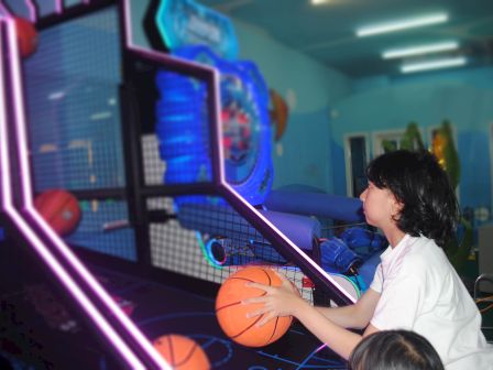 A child is playing an arcade basketball game, aiming to shoot the ball.