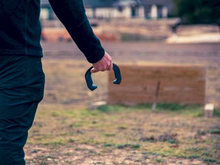 A person holding horseshoes, preparing to play a game of horseshoes outdoors.