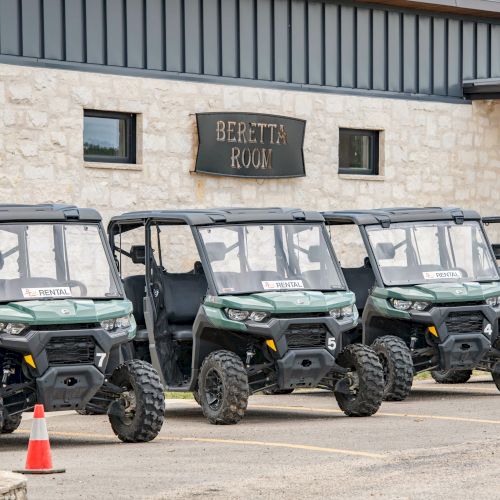 The image shows a row of green off-road utility vehicles parked in front of a building with a sign that reads "BEFITTE ROW."