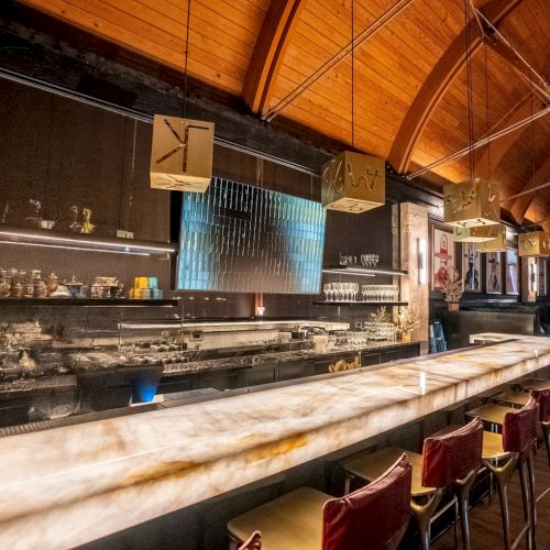 A cozy cafe with warm lighting, wooden bar, stools, and shelves; a chalkboard menu, plants, and a relaxed social vibe.