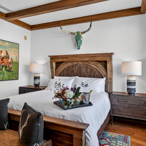 A cozy living room with a fireplace, two framed artworks, a dark wooden coffee table, and a pair of matching sofas facing a TV, under warm lighting.