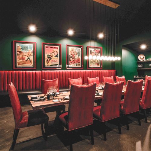 A cozy bar scene with red stools at a long counter, dim lighting, and shelves of bottles in the background, inviting a night out.