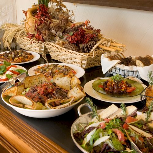 A buffet spread with various dishes and salads is displayed on a table with decorative baskets in the background.