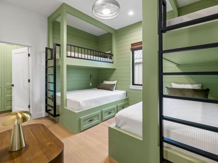 A bright green kids&rsquo; bunk room with two stacked beds, a daybed, and a ceiling light.