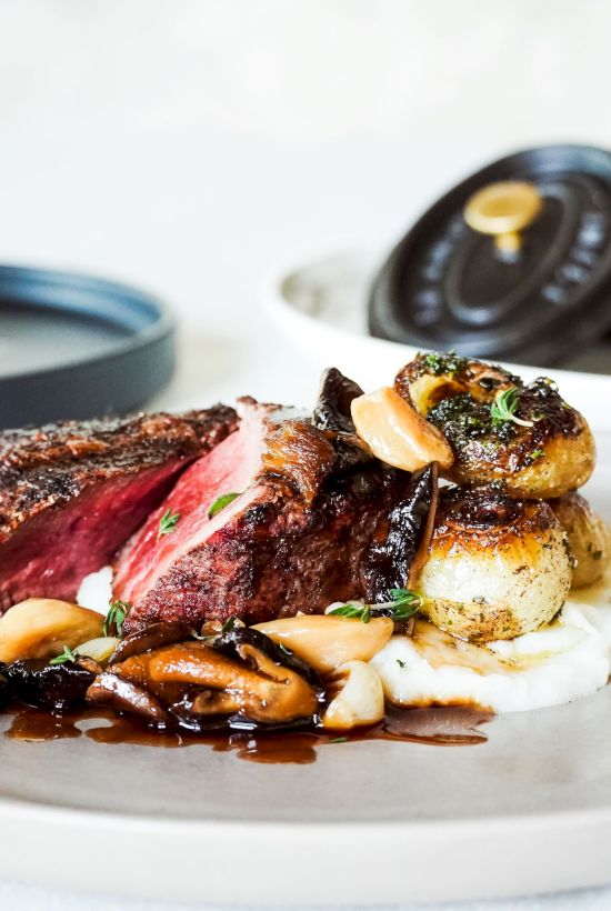 A gourmet dish featuring a perfectly cooked steak, garnished with vegetables and sauce, elegantly plated for fine dining.