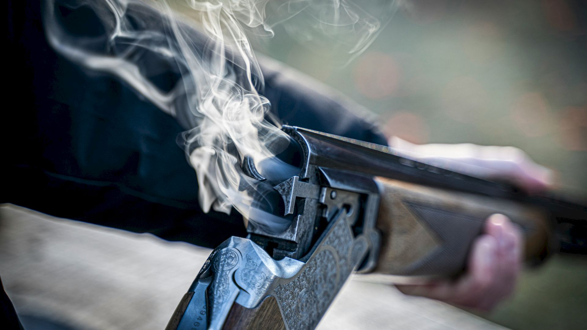 A close-up of a handgun firing, with bright muzzle smoke billowing from the barrel.