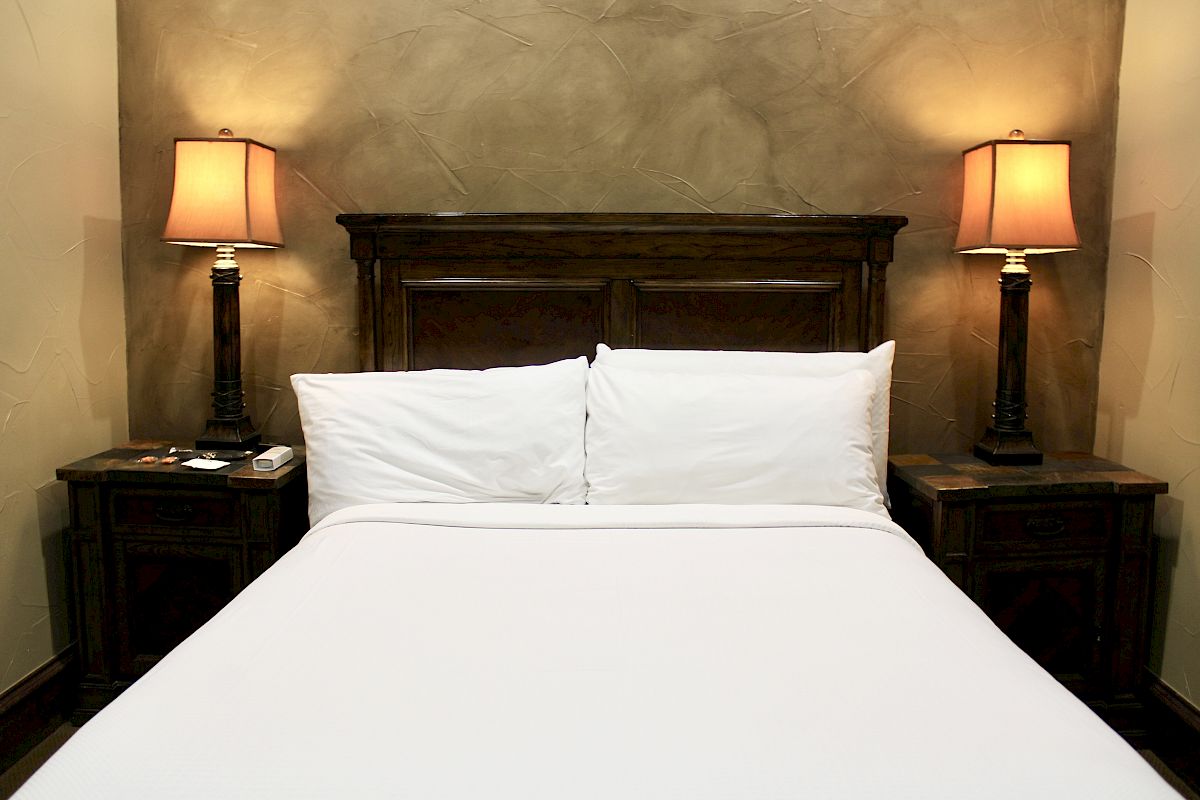 A cozy bedroom with a made bed, twin lamps on bedside tables, and warm-colored textured walls.