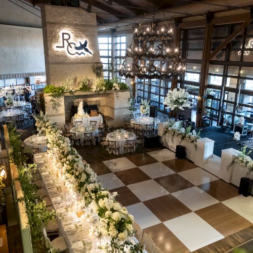 A decorated event space with tables, floral arrangements, chandeliers, and a checkered dance floor is visible.