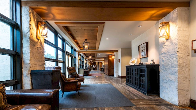 A cozy hallway with wooden floors, armchairs, warm lighting, and large windows, creating an inviting and stylish atmosphere.