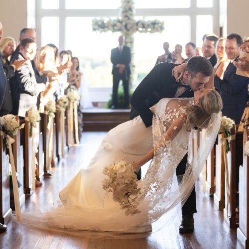 A golden retriever sits among people in a store, calmly observing shoppers as they pass by.