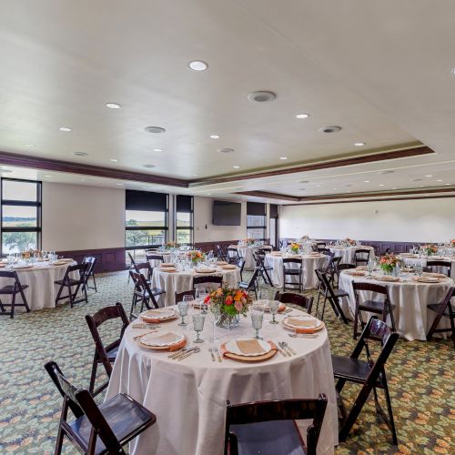 Modern cafe or bakery interior with large windows, wooden tables, and warm lighting. A few customers sit and work; counter area in background. 140 characters total, ending with a period.