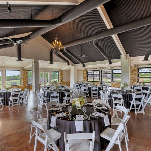 A bright, airy cafe or coworking space with wooden beams, plants, and tables; people sit and chat or work with laptops.