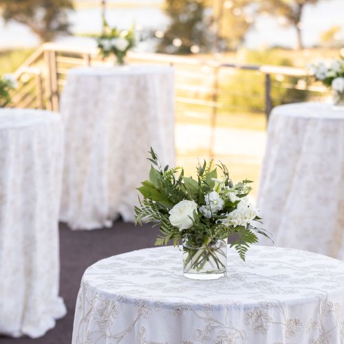A wedding reception table with a white tablecloth, floral centerpiece, and soft, elegant decor.