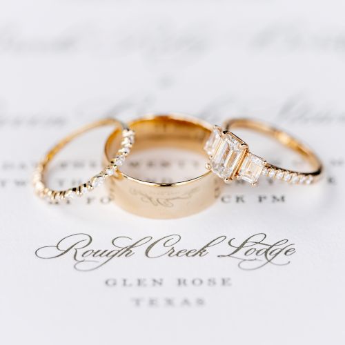 A displayed ring on a soft background with a handwritten note beneath, photographed in warm, close-up lighting.