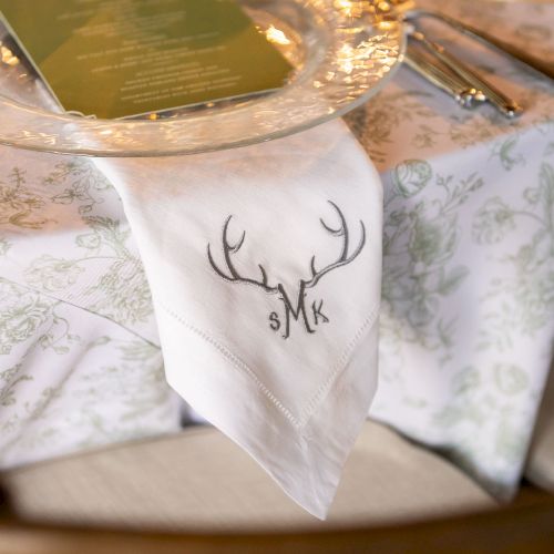 A cozy table setting with a deer-etched napkin ring, warm candlelight, and rustic place settings.